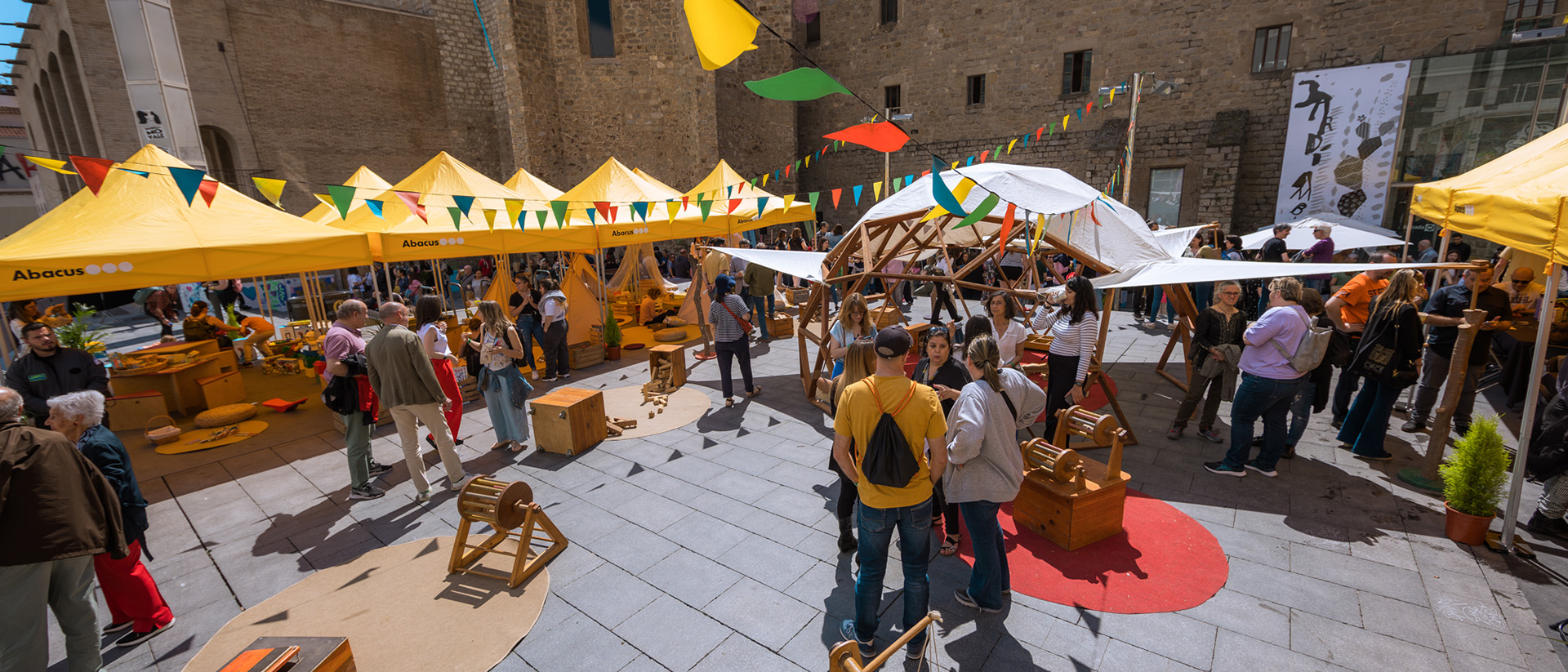 Foto panorámica de un grupo de personas en una celebración del Día Abacus, con banderas y camisetas de la cooperativa.